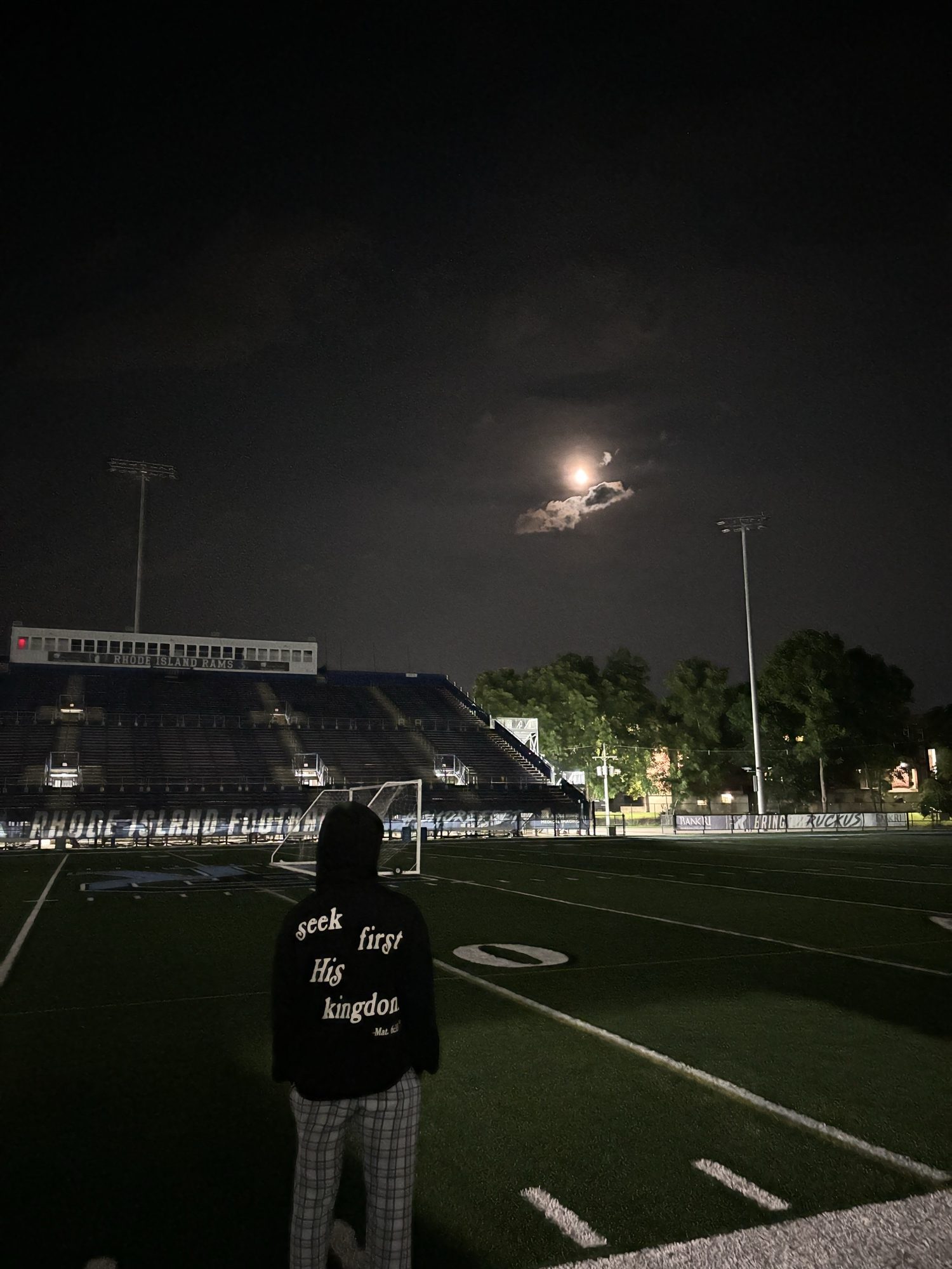 Someone standing on a football field at night under a bright moon