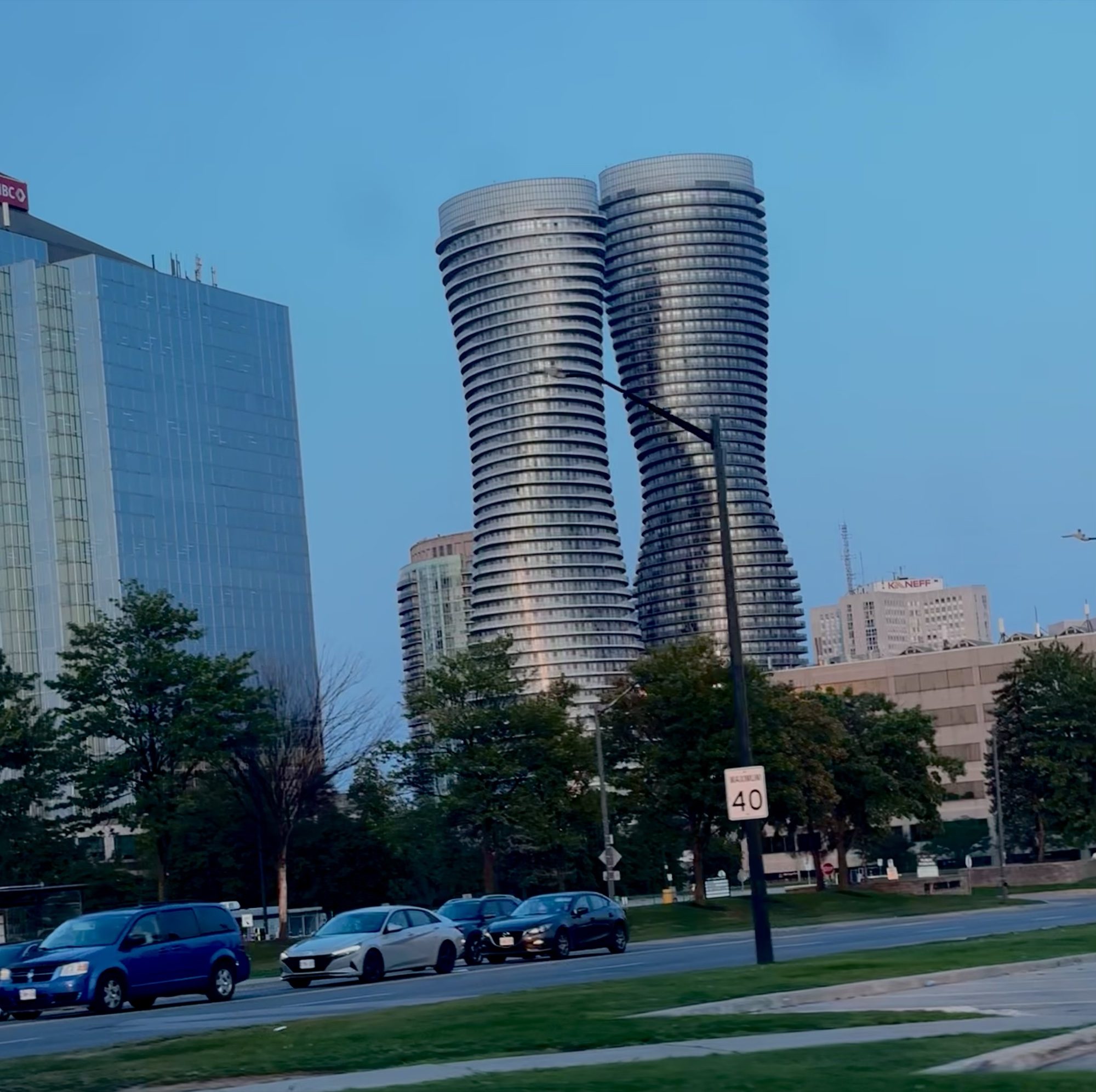 The curving Absolute World towers beside a tree-lined road