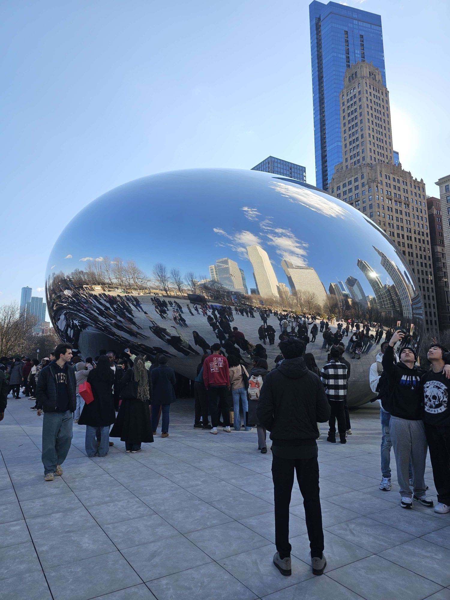 Crowd gathered around Cloud Gate, the mirrored “Bean” sculpture, under the skyline