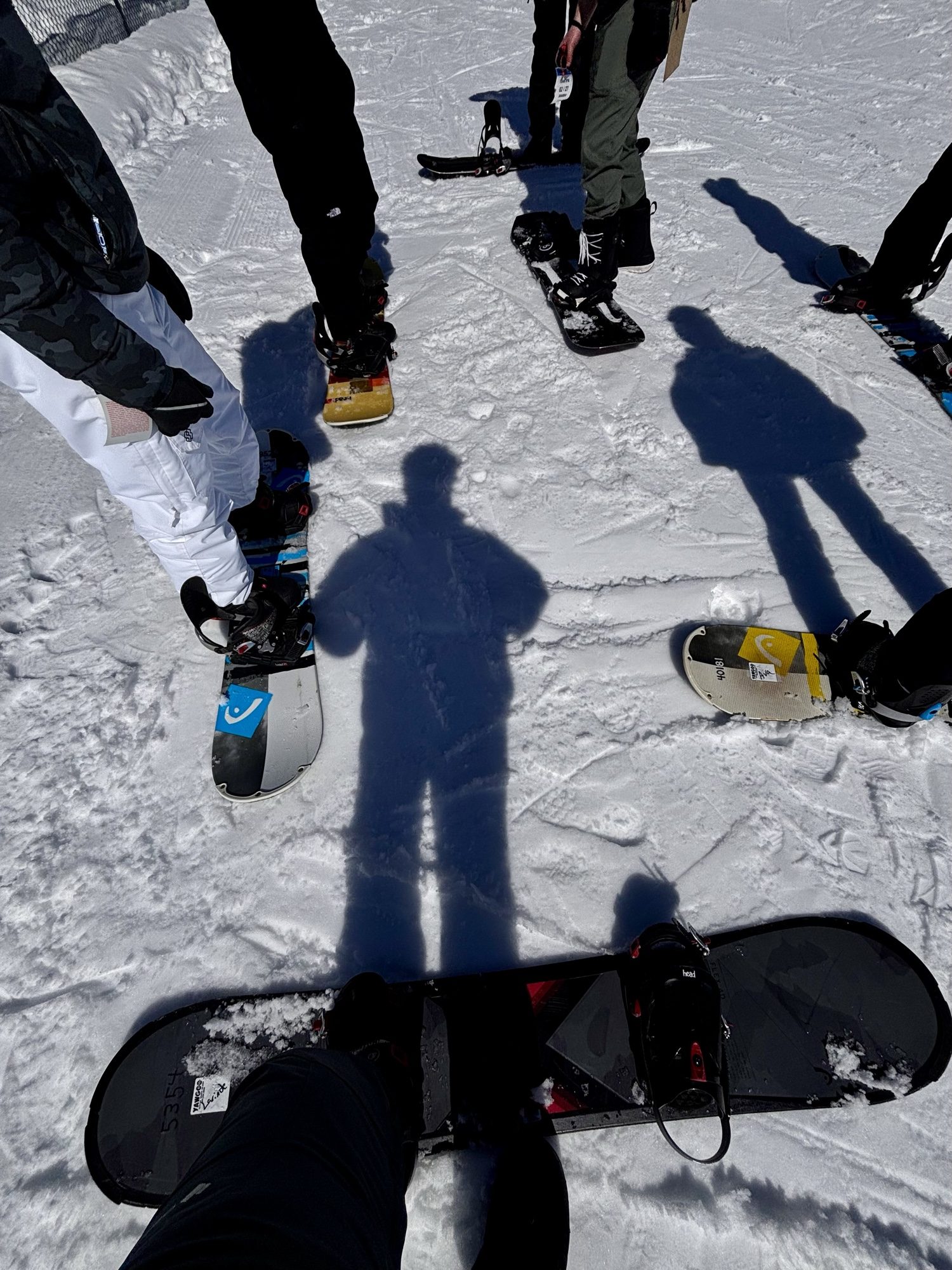 Snowboarders’ boards and shadows on the snow