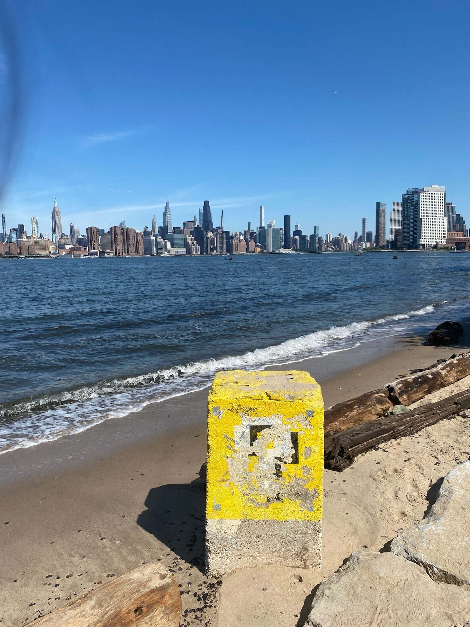 Manhattan skyline across the water from a sandy beach